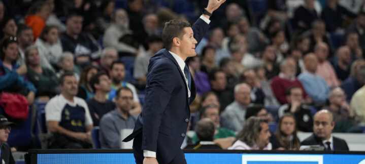 Entrenador gesticulando con entusiasmo durante un partido de baloncesto.