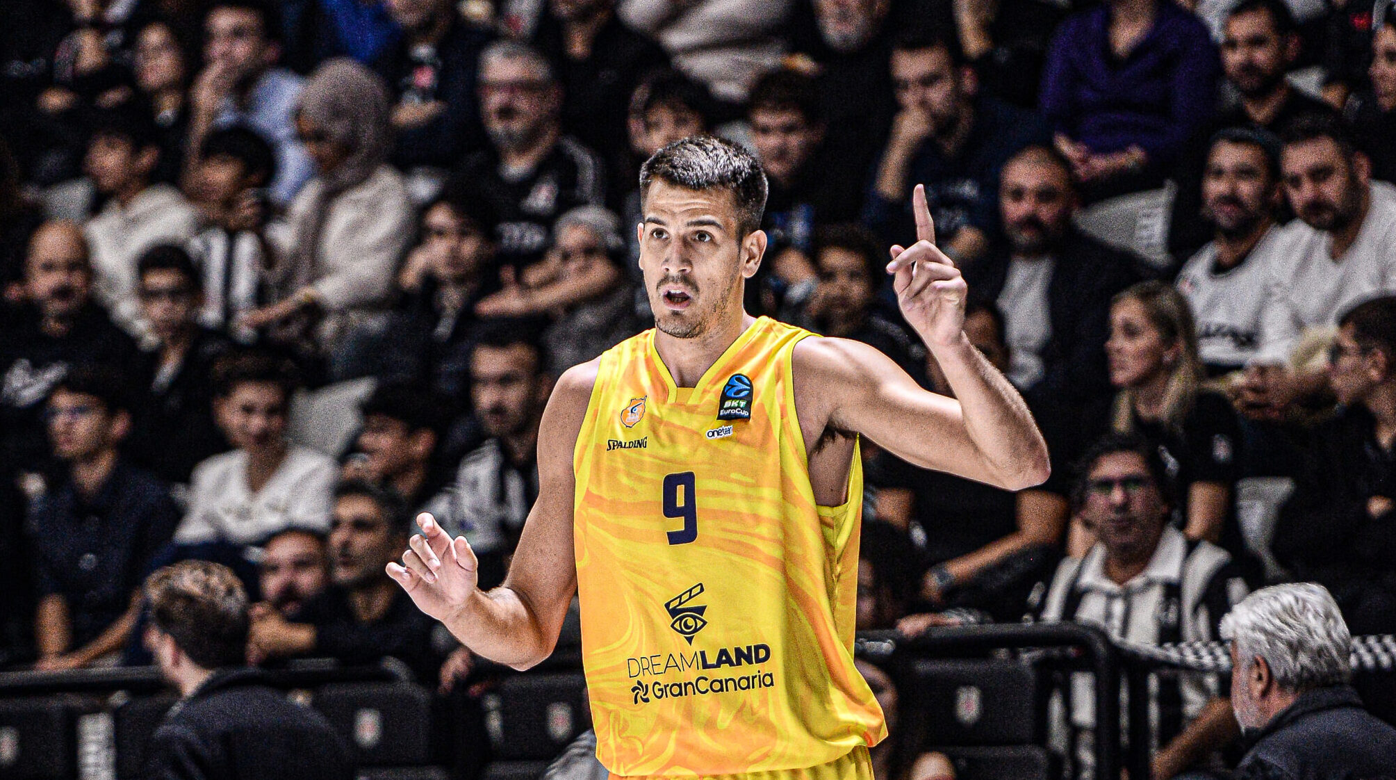 Jugador del Club Baloncesto Gran Canaria señalando, con aficionados al fondo.