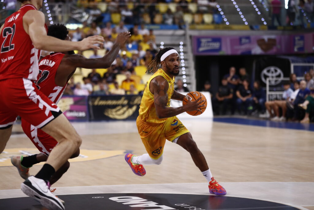 Jugador driblando con un balón de baloncesto, en acción durante un partido.