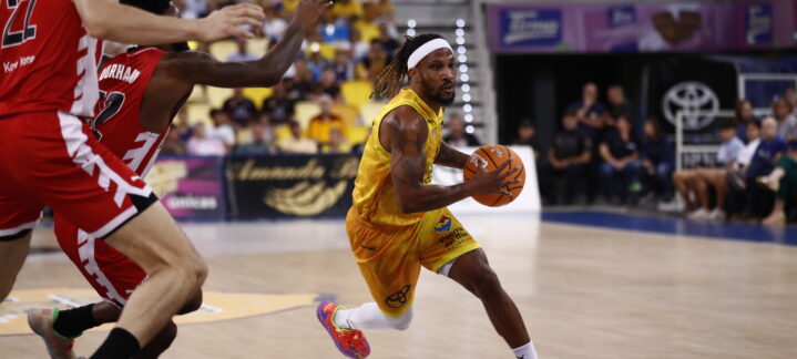 Jugador driblando con un balón de baloncesto, en acción durante un partido.