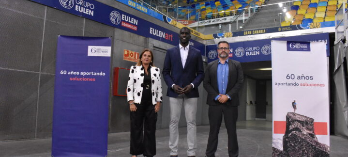 Tres personas posan frente a pancartas con el lema ""60 años aportando soluciones"" en un evento.