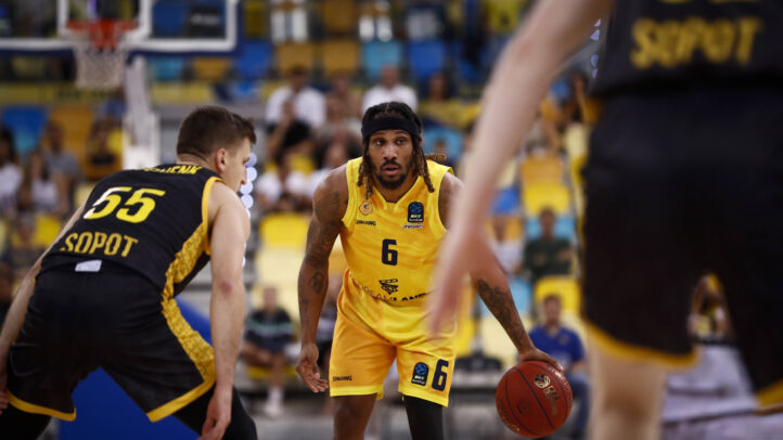 Jugador con balón en acción durante un partido de baloncesto contra Sopot.