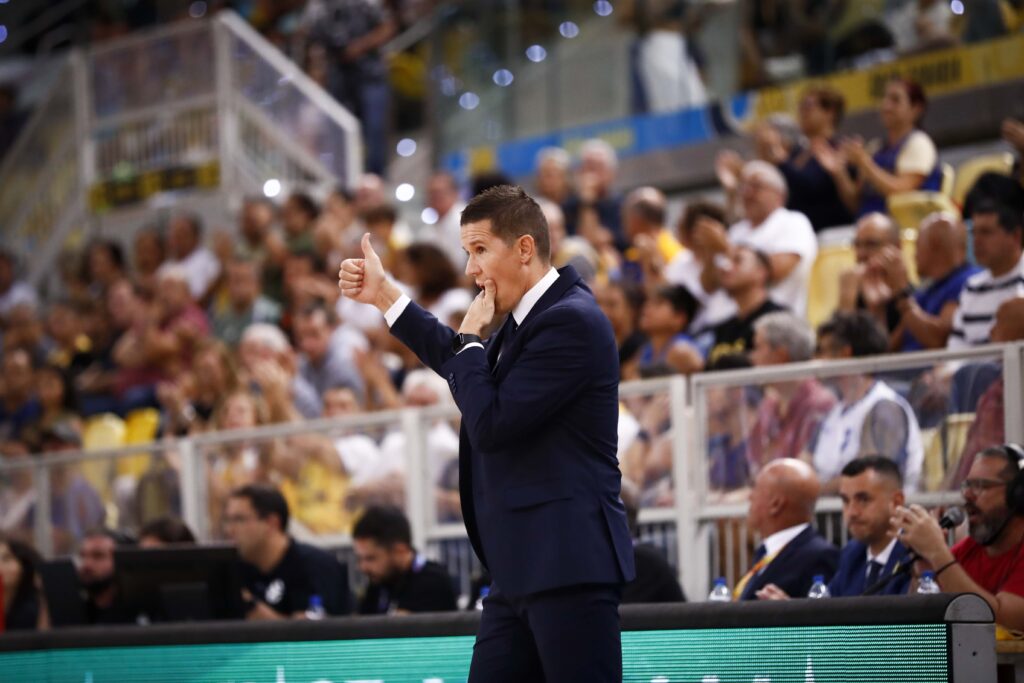 Entrenador gesticulando con un pulgar hacia arriba mientras dirige desde la línea de banda.
