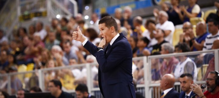 Entrenador gesticulando con un pulgar hacia arriba mientras dirige desde la línea de banda.