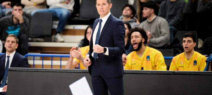 Entrenador de baloncesto dirigiendo a su equipo, con jugadores y aficionados animando.