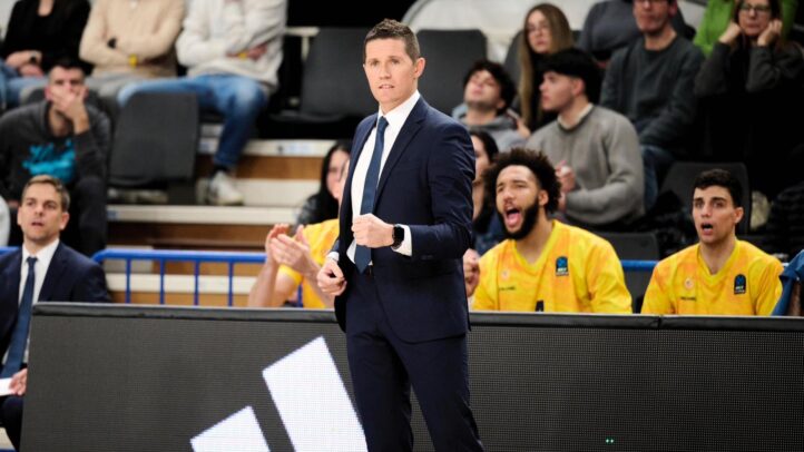 Entrenador de baloncesto dirigiendo a su equipo, con jugadores y aficionados animando.