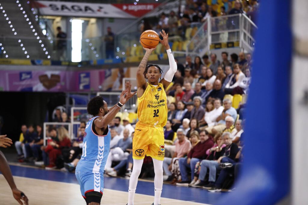 Jugador del Dreamland Gran Canaria lanza a canasta mientras es defendido en un partido.
