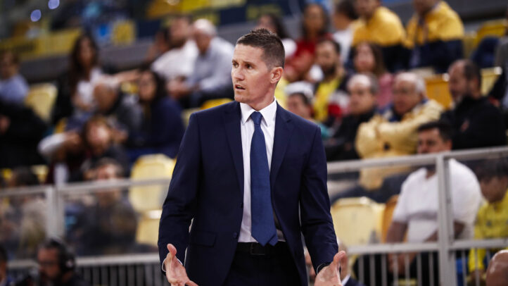 Entrenador gesticulando durante un partido con público en las gradas.