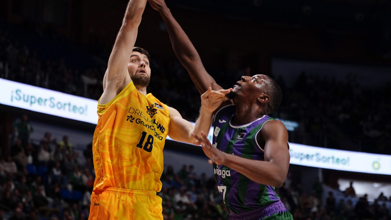 Jugador del Gran Canaria lanza a canasta bajo la defensa de un oponente en el Carpena.