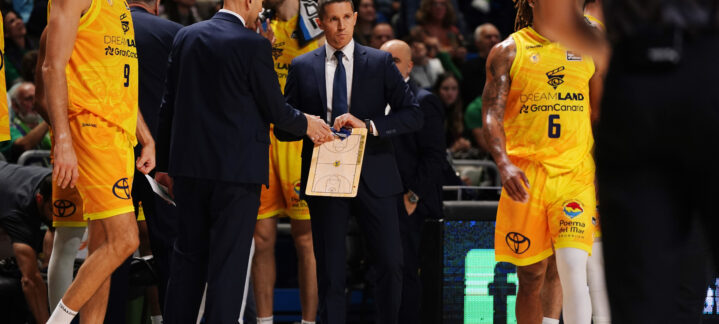 Entrenador y jugadores del CB Gran Canaria discutiendo estrategias durante un partido.