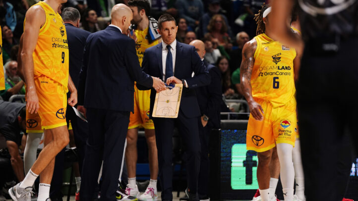 Entrenador y jugadores del CB Gran Canaria discutiendo estrategias durante un partido.