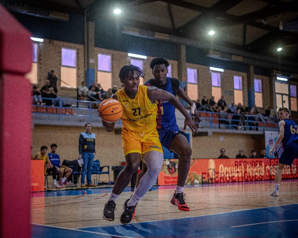 Jugadores de baloncesto compiten en el Torneig Ciutat de L'Hospitalet, mientras uno dribla.