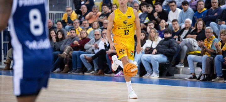 Jugador del Dreamland Gran Canaria con balón, en pleno partido, frente a un público animado.