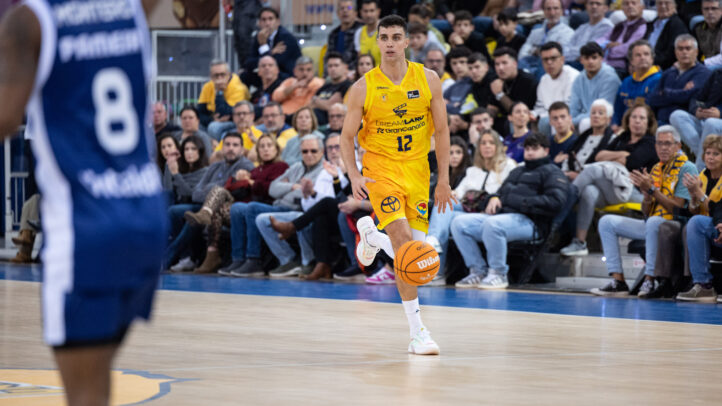 Jugador del Dreamland Gran Canaria con balón, en pleno partido, frente a un público animado.