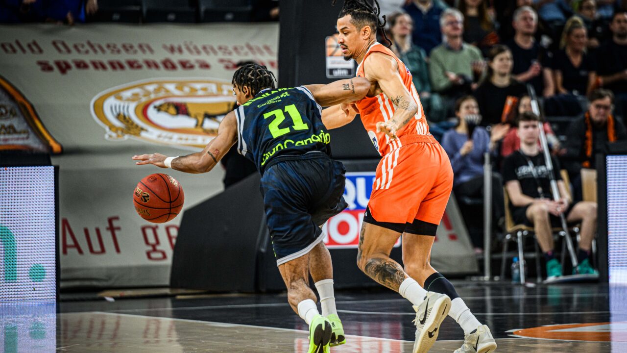 Dos jugadores de baloncesto compiten por el control del balón en la cancha.