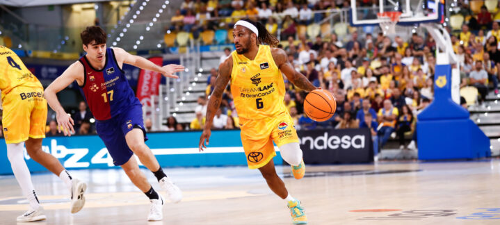 Jugadores de baloncesto en acción, con un atleta en amarillo avanzando con el balón.