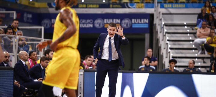 Entrenador dirigiendo al equipo durante un partido, gesticulando y animando a los jugadores.