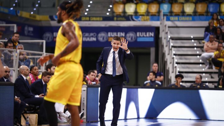 Entrenador dirigiendo al equipo durante un partido, gesticulando y animando a los jugadores.