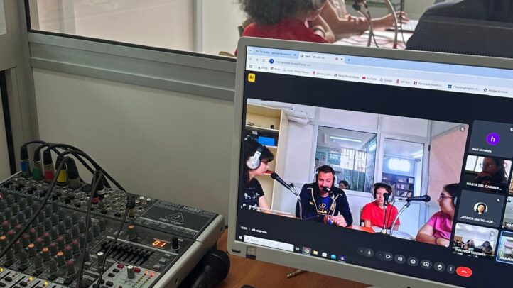 Estudio de grabación con personas hablando y una pantalla mostrando una videoconferencia.