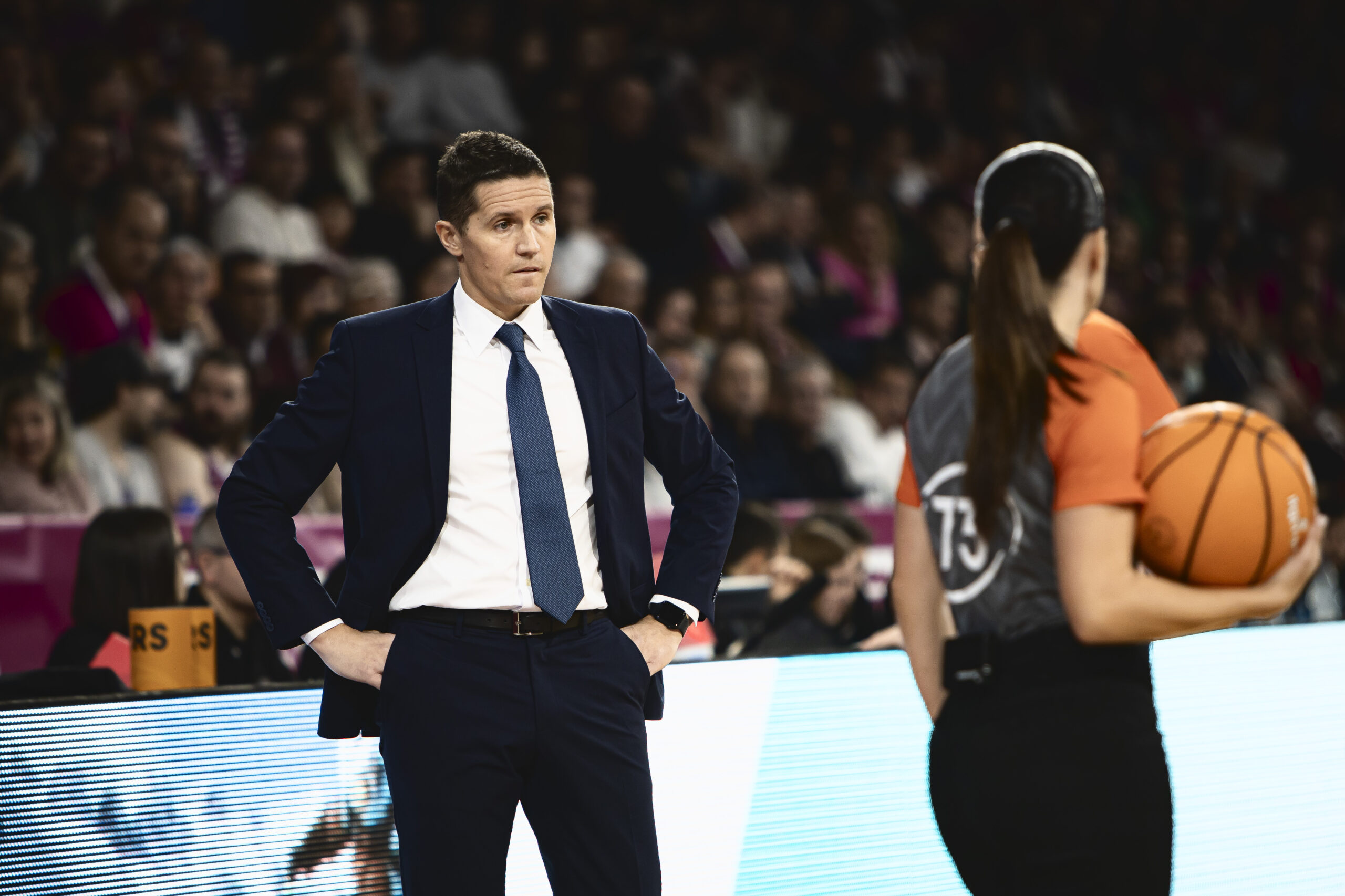 Jaka Lakovic observa un partido, con un árbitro sujetando un balón cerca de él.