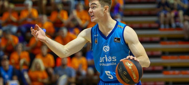 Jugador de baloncesto gesticulando y sosteniendo un balón en un partido.