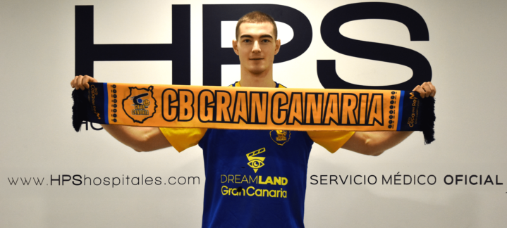 ya en la isla: ""Siempre doy el máximo, es mi forma de ser""","Jugador sosteniendo una bufanda del CB Gran Canaria, sonriendo en una sala.