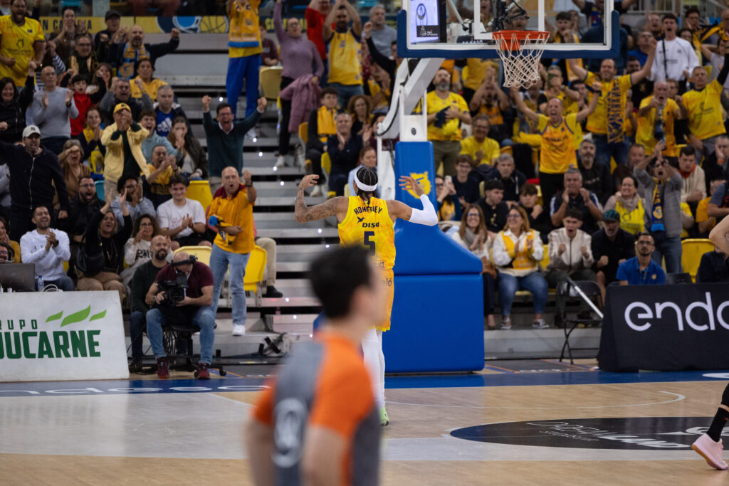 Jugadores y aficionados celebran un momento emocionante en un partido de baloncesto.