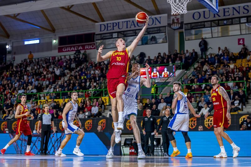 Jugador español en acción durante un partido de baloncesto, intentando anotar.