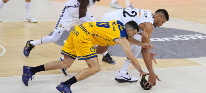 Jugadores de baloncesto compiten por el balón en un partido intenso en la pista.