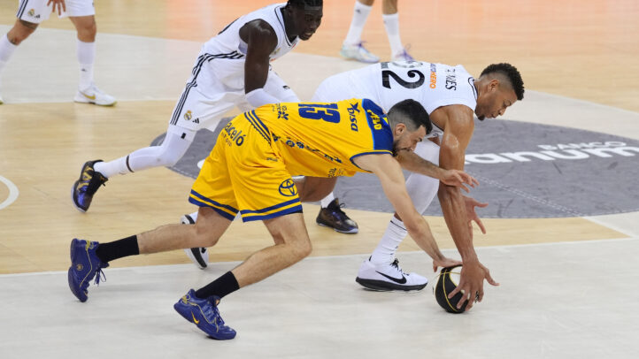 Jugadores de baloncesto compiten por el balón en un partido intenso en la pista.