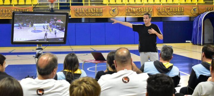 unidos en una fructífera formación de entrenadores",Taller de formación de entrenadores con Carlos Frade y una pantalla mostrando jugadas.