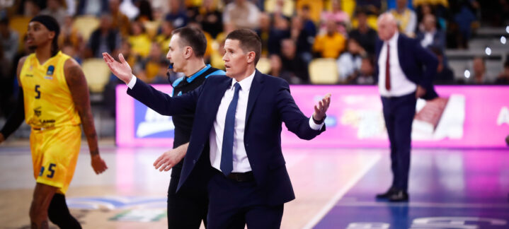 Entrenador gesticulando al dar instrucciones durante un partido de baloncesto.