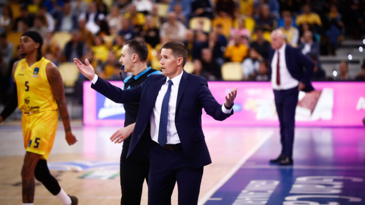 Entrenador gesticulando al dar instrucciones durante un partido de baloncesto.