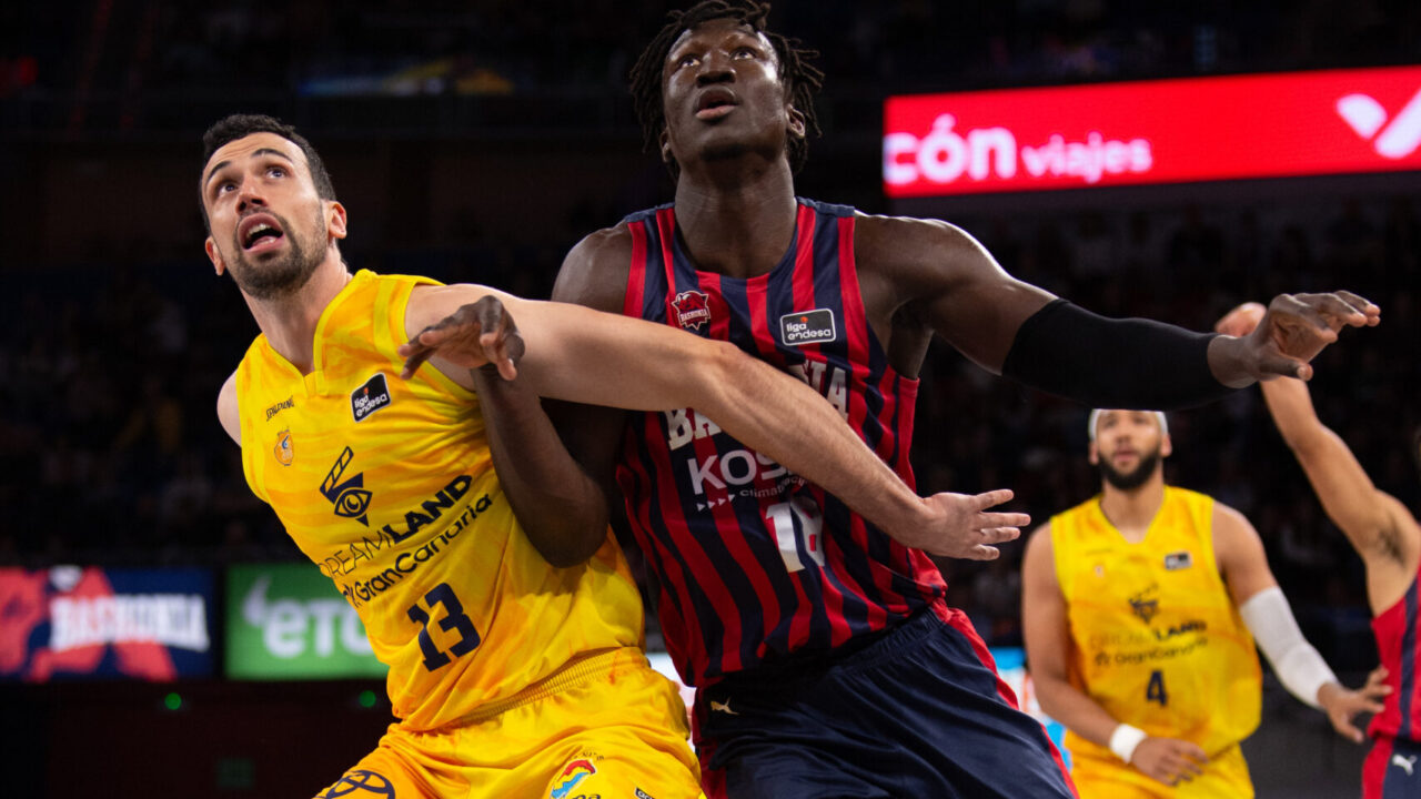 Dos jugadores de baloncesto compiten por el balón en un partido vibrante.