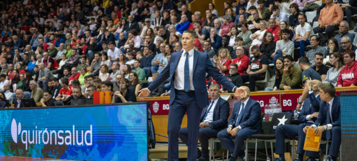 Entrenador dirigiendo a su equipo desde la banda en un partido de baloncesto.