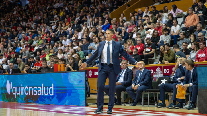 Entrenador dirigiendo a su equipo desde la banda en un partido de baloncesto.