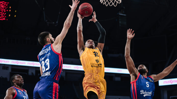 Jugador del Dreamland Gran Canaria lanza a canasta mientras es defendido por oponentes.