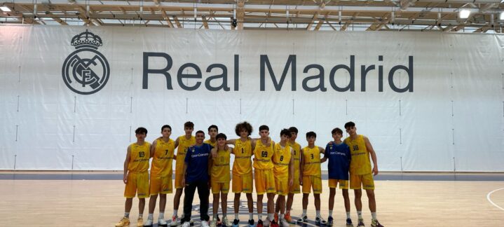 Grupo de jóvenes baloncestistas en la cancha del Real Madrid, luciendo uniformes amarillos.