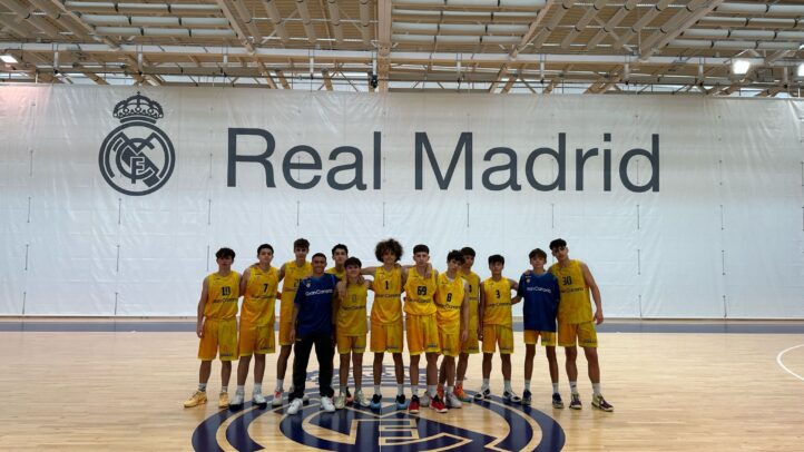 Grupo de jóvenes baloncestistas en la cancha del Real Madrid, luciendo uniformes amarillos.