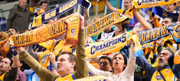 adquiere tu entrada para la final de la BKT EuroCup antes del lunes 7",Aficionados del Club Baloncesto Gran Canaria animan con bufandas en un evento deportivo.