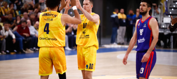 Dos jugadores del Gran Canaria celebran un punto, mientras un rival observa.