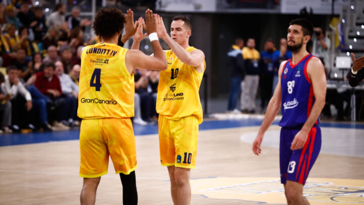 Dos jugadores del Gran Canaria celebran un punto, mientras un rival observa.