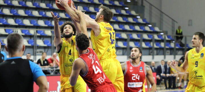 Jugadores de baloncesto en acción durante un partido, uno lanzando a canasta.