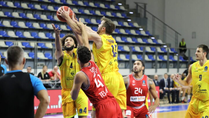 Jugadores de baloncesto en acción durante un partido, uno lanzando a canasta.