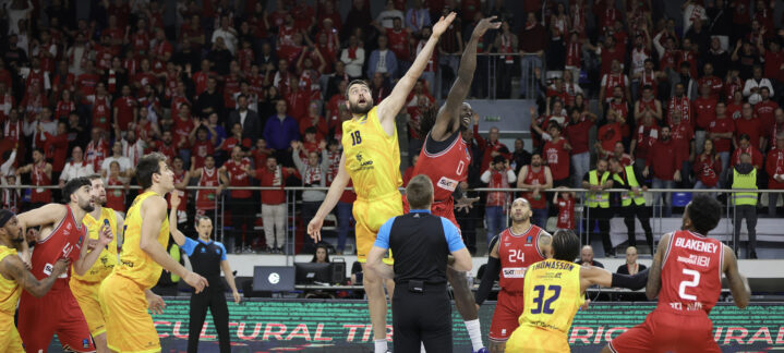 Salto inicial entre jugadores de baloncesto en un ambiente de gran expectación.