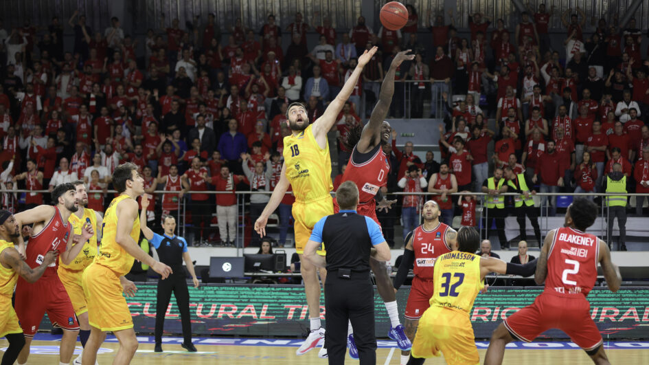 Salto inicial entre jugadores de baloncesto en un ambiente de gran expectación.
