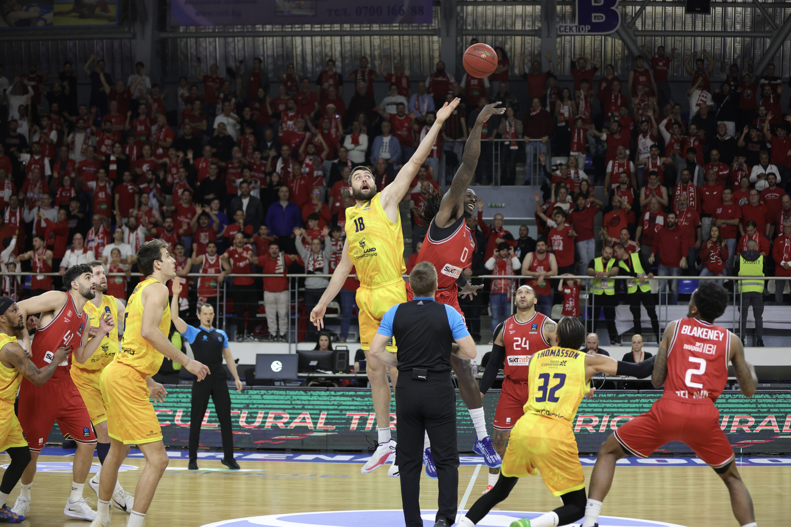 Salto inicial entre jugadores de baloncesto en un ambiente de gran expectación.