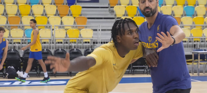 Entrenador instruye a un jugador de baloncesto en la cancha durante un entrenamiento.