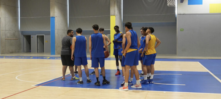 Grupo de jugadores de baloncesto reunidos en una cancha durante un entrenamiento.