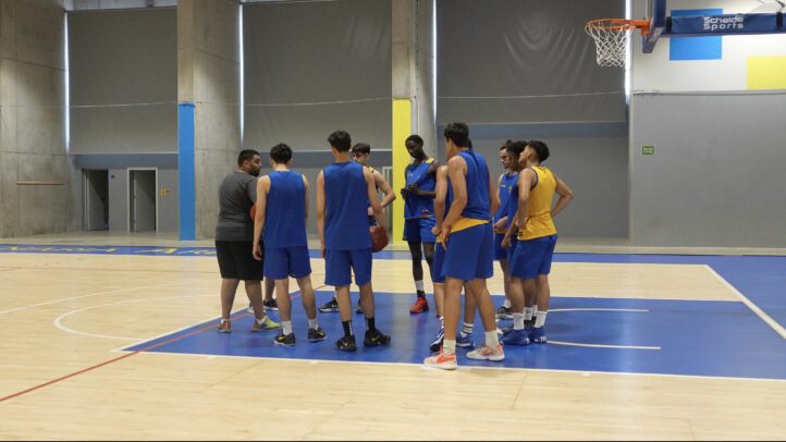 Grupo de jugadores de baloncesto reunidos en una cancha durante un entrenamiento.